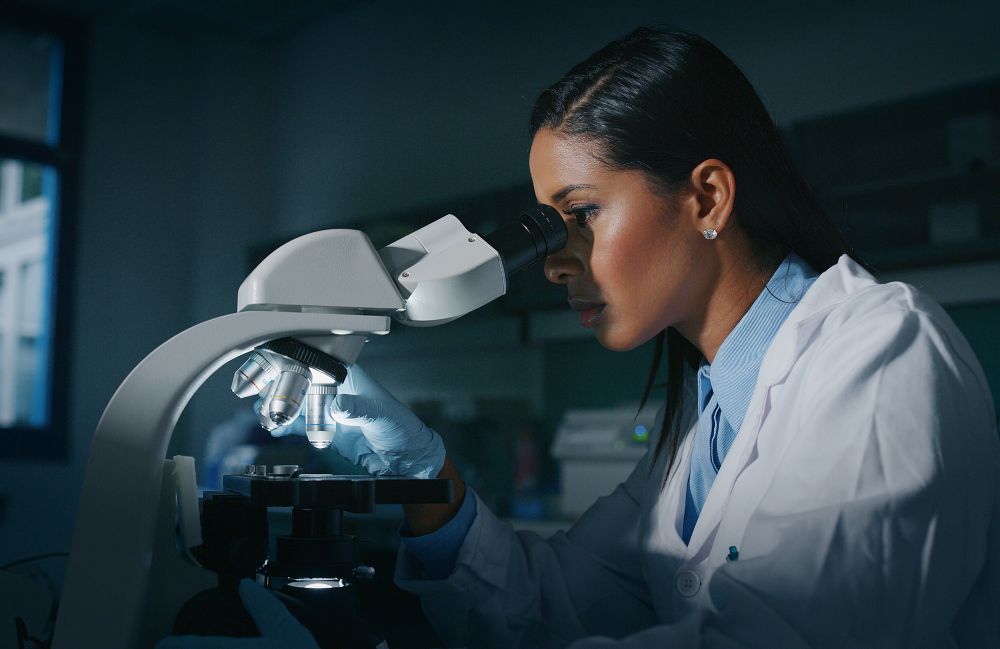 A dermatologist inspecting a skin biopsy with a magnifying glass during a dermatopathology evaluation in Costa Mesa.