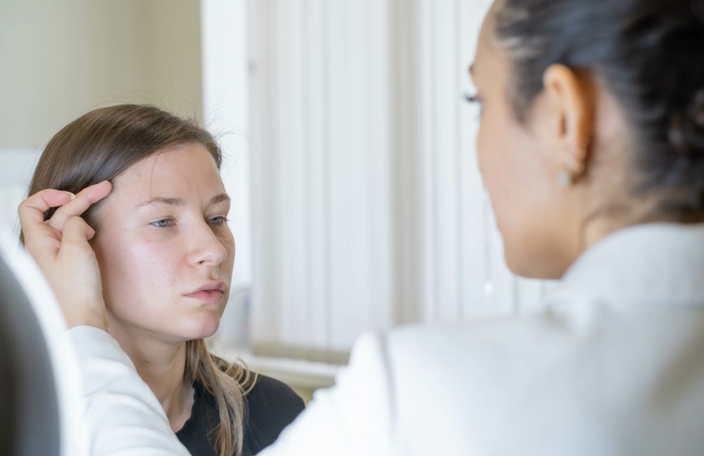 A dermatologist examining a woman's skin during a consultation in Costa Mesa, focusing on facial concerns.