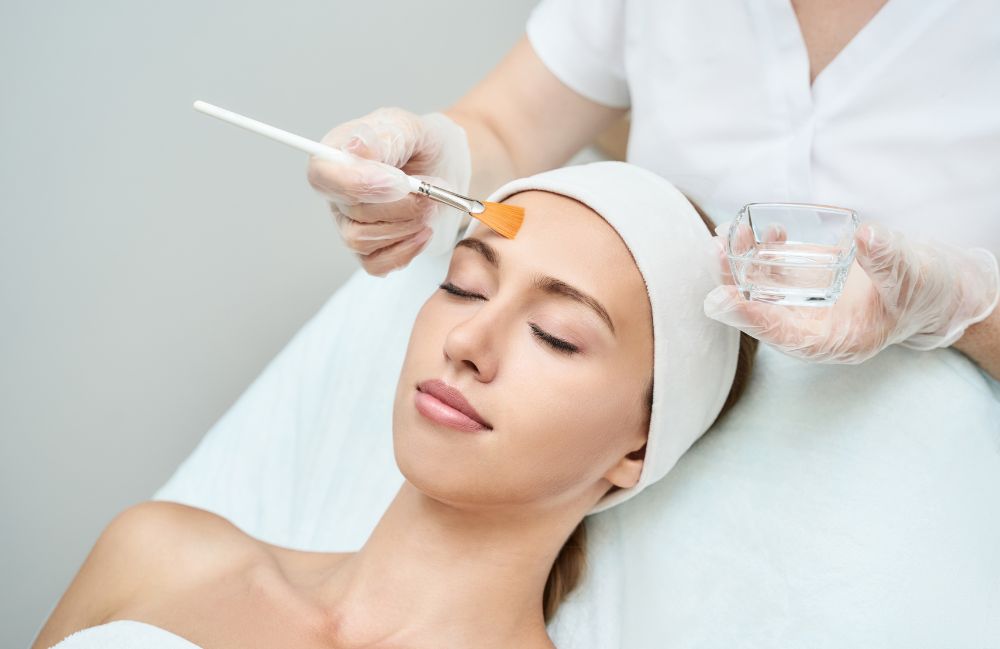 A woman receiving a chemical peel treatment with a brush at a spa in Costa Mesa.