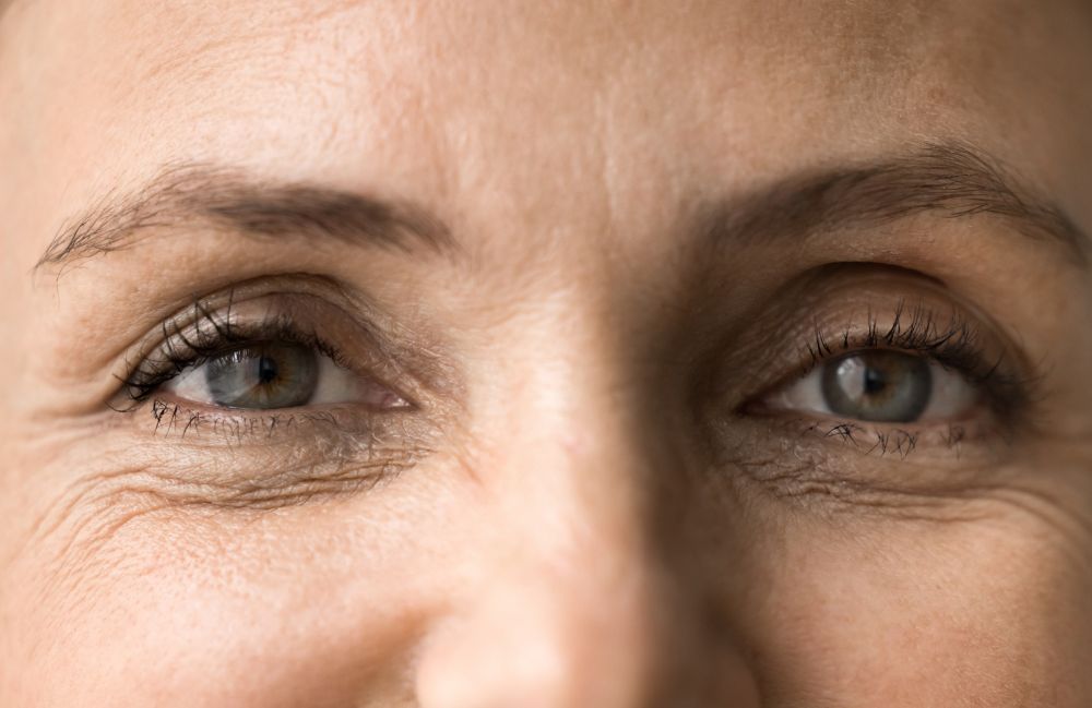 Smiling woman with glowing skin gently touching her face, representing facial treatments in Costa Mesa.